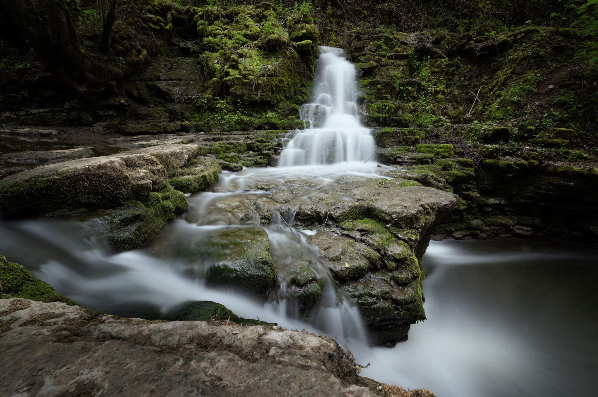 Kleiner Wasserfall in Mitten eines steinigen Waldstückes