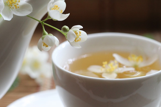 Zarte weiße Blüten mit verschwommener Aufnahme einer weißen Tee-Tasse im Hintergrund