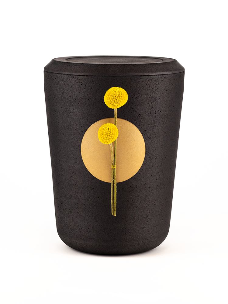 Schwarze Asche-Urne mit goldenem Punkt & zwei gelben kugelförmigen Blüten in der Mitte